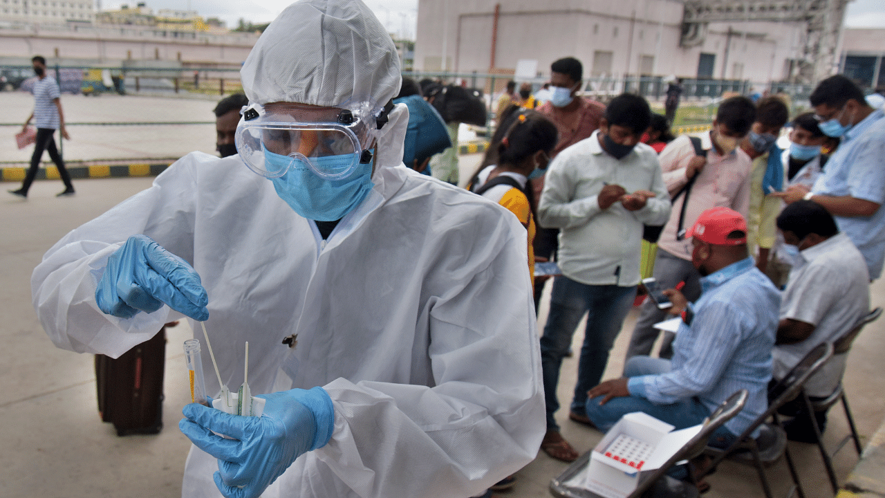 A healthcare worker collects swab samples for coronavirus from people at KSRTC bus stand Majestic. Credit: DH Photo
