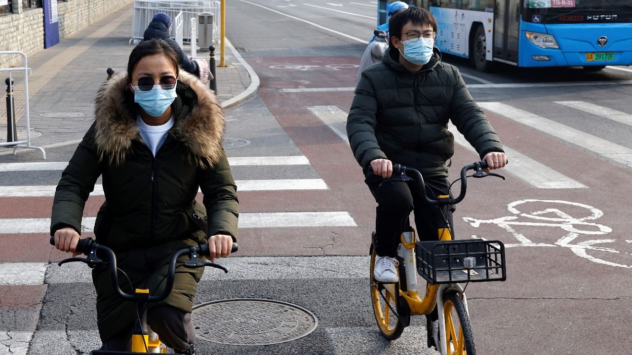 People wearing protective masks ride bicycles in Beijing. Credit: Reuters Photo