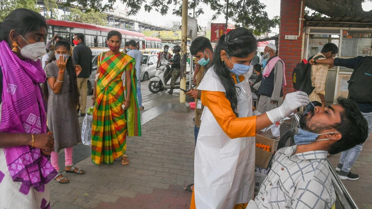A health worker collects nasal swabs at Kempegowda KSRTC bus stand in Majestic, Bengaluru, on Sunday. Credit: DH Photo/S K Dinesh