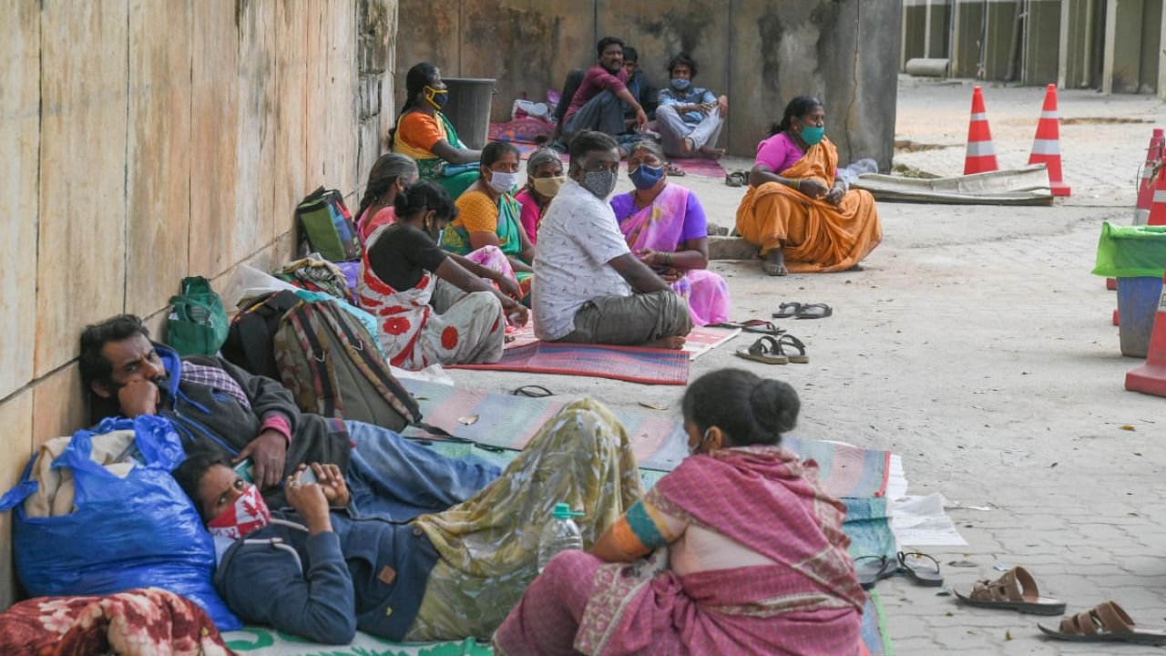 With no place to stay, patients' bystanders wait outside Gosha Hospital in Shivajinagar on Monday. Credit: DH photo/S K Dinesh