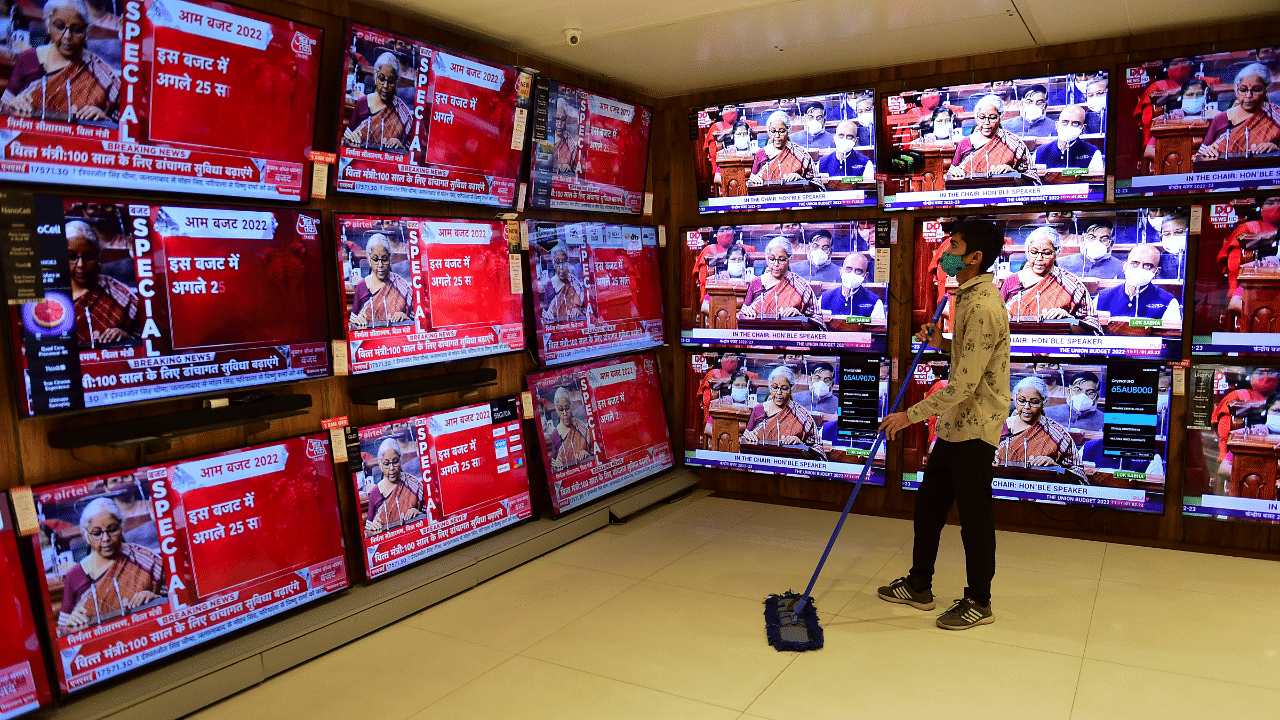 A store worker cleans works as TV sets show the live telecast of Finance Minister Nirmala Sitharaman's tabling of the Union Budget- 2022. Credit: PTI Photo