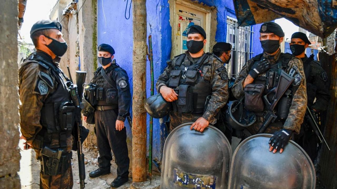 In this photo released by TELAM, security forces stand guard during a raid in Taller Puerta 8 shantytown, Buenos Aires province. Credit: AFP Photo/Telam/Eliana Obregon