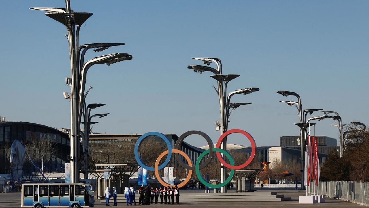 Staff members pose in front of Olympics Rings outside the National Stadium, also known as the Bird's Nest, ahead of the Beijing 2022 Winter Olympics, in Beijing. Credit: Reuters Photo