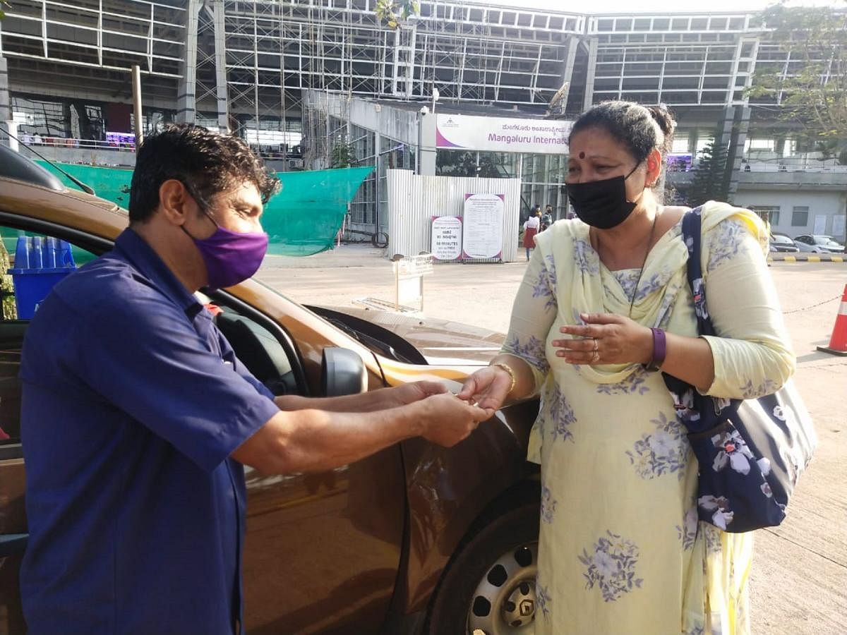 Ashraf Moideen, who is serving as a trolley retriever at Mangaluru International Airport, hands over the diamond-studded bangle to its rightful owner at the airport on Wednesday.