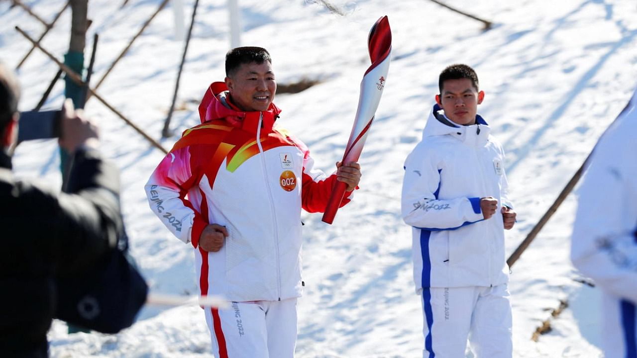Torch bearer Qi Fabao, a regimental commander in the People's Liberation Army, relays the Olympic flame at the Winter Olympic Park. Credit: Reuters photo