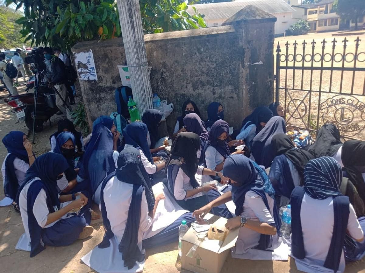 Hijab clad girl students sitting outside the gate of Government PU College in Kundapura. Credit: DH Photo