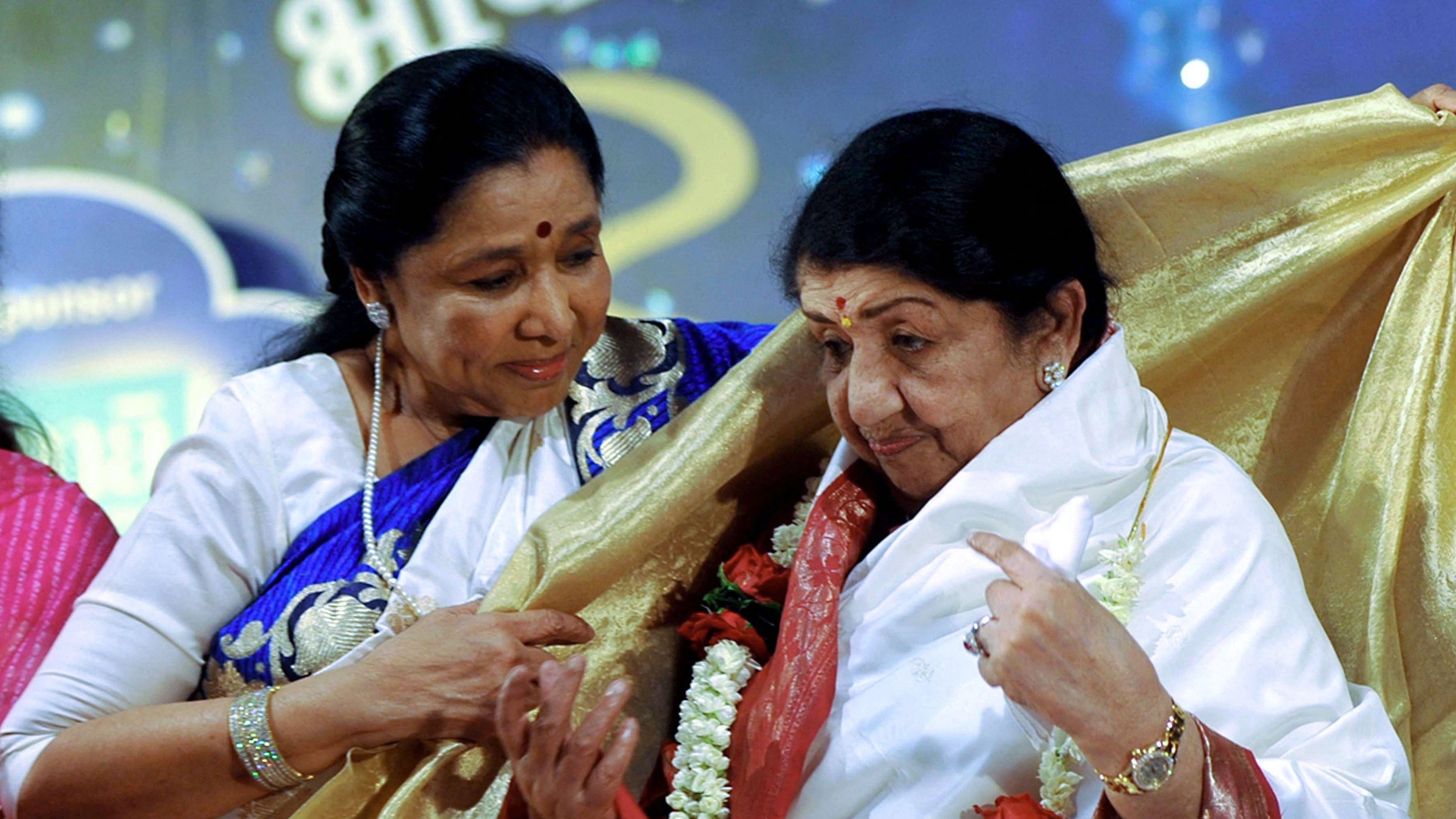 Lata Mangeshkar (R) is greeted by her sister Asha Bhosle during the Pandit Hridaynath Mangeshkar’ Awards in Mumbai.Credit: AFP File Photo