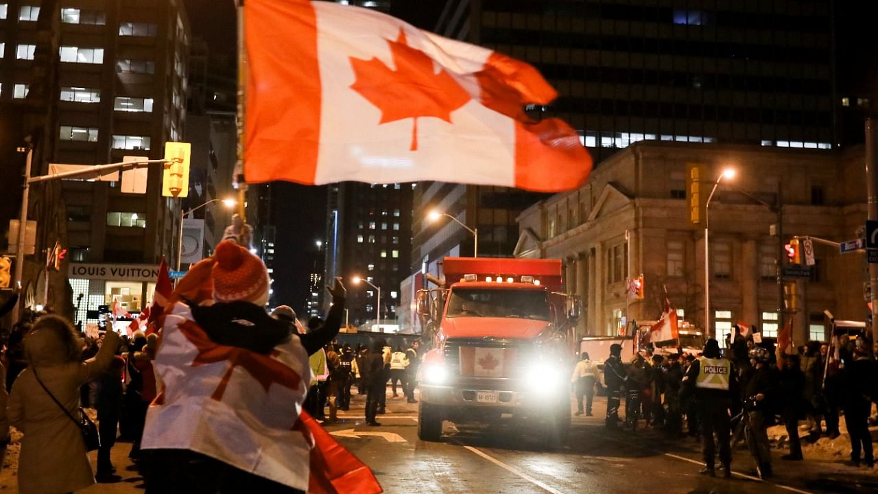 People gather in the street as a truck leaves during a protest by truckers and supporters against coronavirus  vaccine mandates, in Toronto. Credit: Reuters Photo