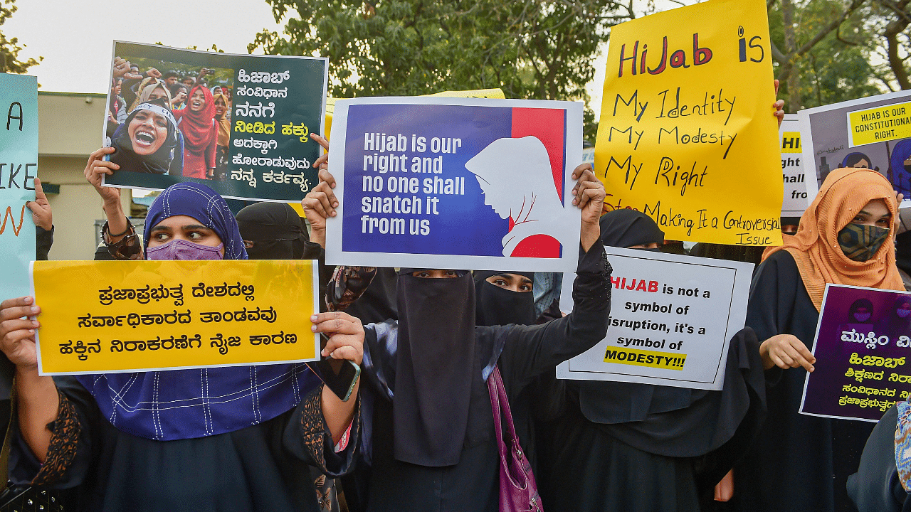 Muslim women hold placards while wearing burqa and hijab to stage a demonstration in support of female Muslim students. Credit: PTI Photo