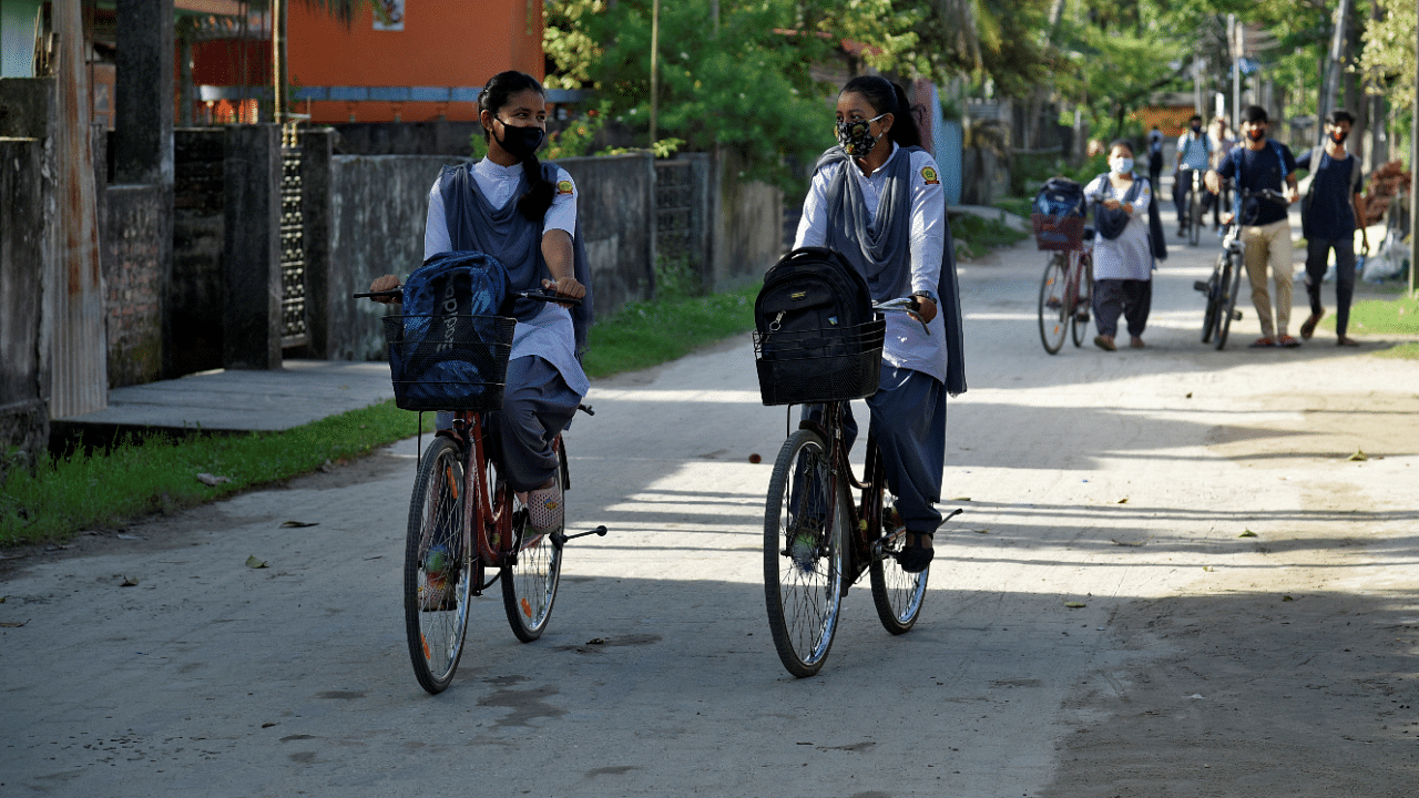 Students wearing protective face masks ride their bicycles as they head to their school to attend their classes after authorities ordered schools to reopen voluntarily for classes 9 to 12, amidst the coronavirus disease outbreak, in Nalbari town in the northeastern state of Assam. Credit: Reuters Photo