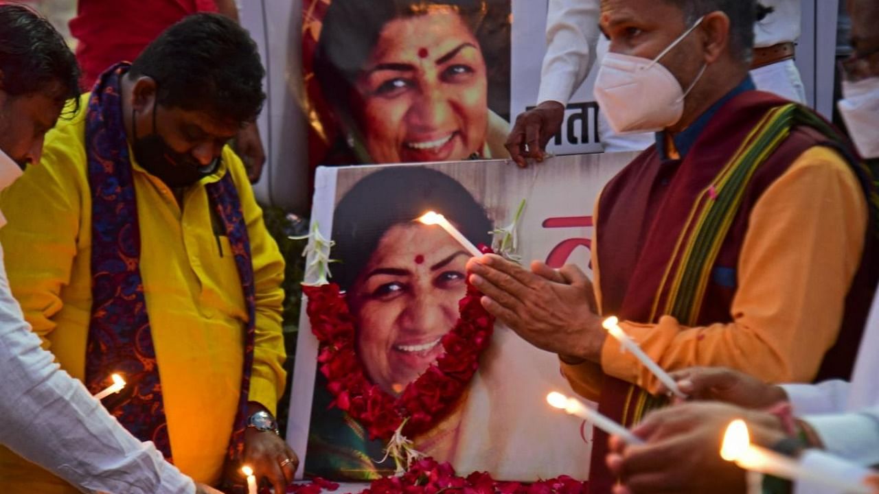 People pay tribute in front of a portrait of Bollywood singer Lata Mangeshkar, in Ahmedabad on February 6, 2022, after she died at the age of 92. Credit: AFP Photo