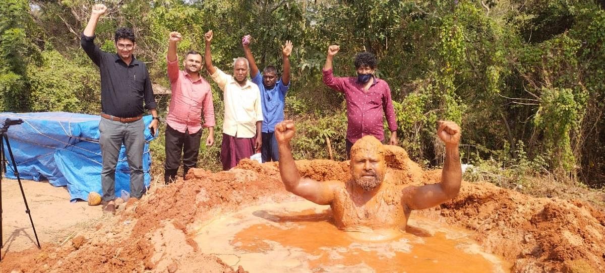 Social worker Asif Apathbhandava staged a novel protest against the toll plaza near NITK, Surathkal on NH 66, by immersing himself in a pit covered with slush on Thursday. Credit: DH Photo