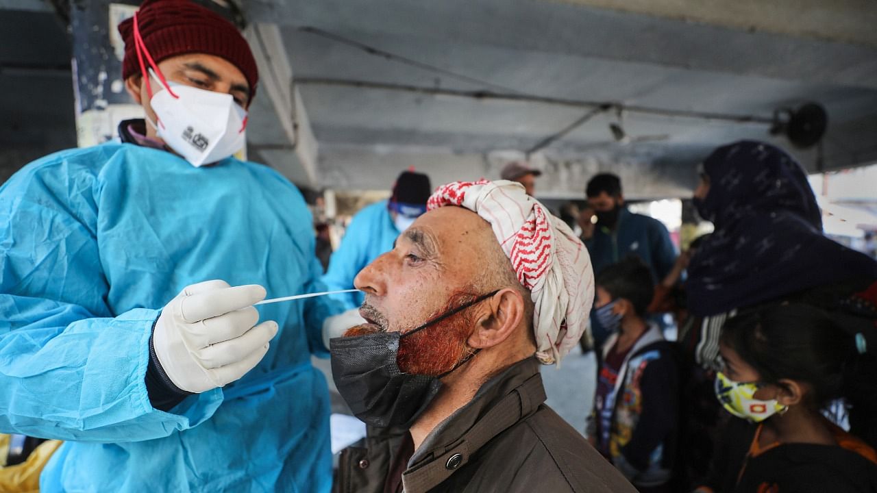 A healthcare worker takes a swab of a passenger for the Covid-19 test, at a bus stand, in Jammu. Credit: PTI Photo