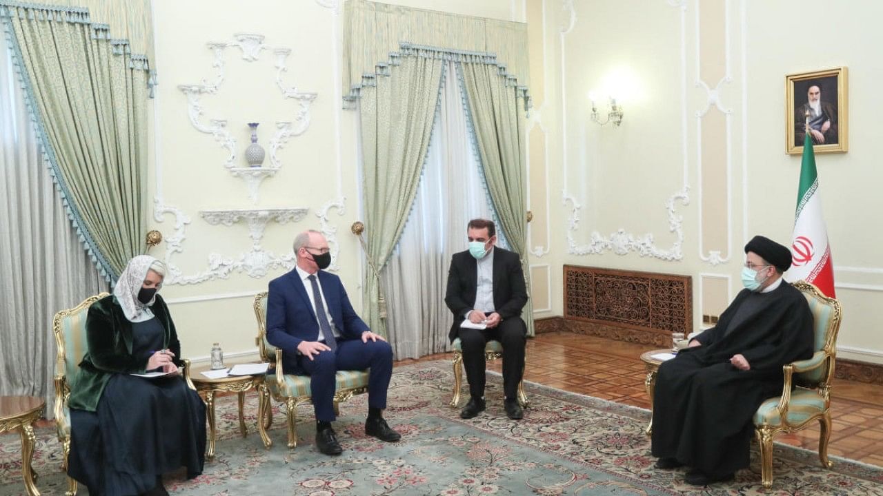 A handout picture provided by the Iranian President Ebrahim Raisi's office shows him (R) meeting with Irish Foreign Minister Simon Coveney (2nd-L) in the capital Tehran. Credit: AFP Photo