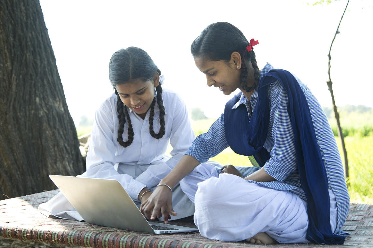 Indian school girls using laptop on field