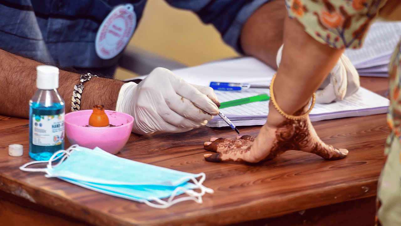 A polling official marks the finger of a woman with indelible ink after she cast her vote during the local body elections. Credit: PTI Photo