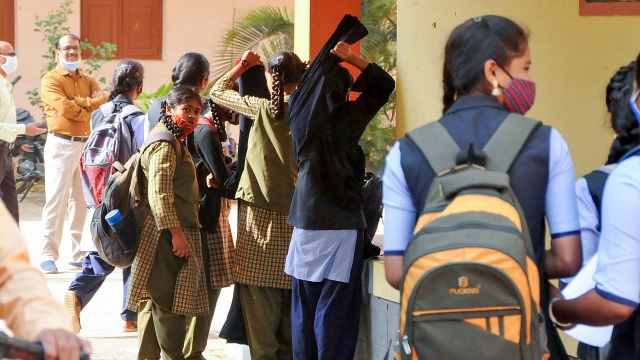 Students take off their hijab after entering the college premises, in Chikmagalur, Friday. Credit: PTI Photo