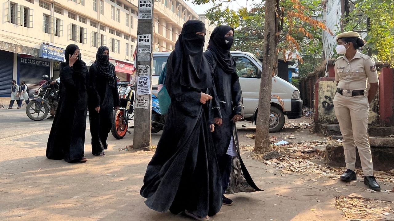 Hijab-wearing students arrive to attend classes as a policewoman stands guard outside a government girls school after the recent hijab ban, in Udupi town in the southern state of Karnataka. Credit: Reuters File Photo