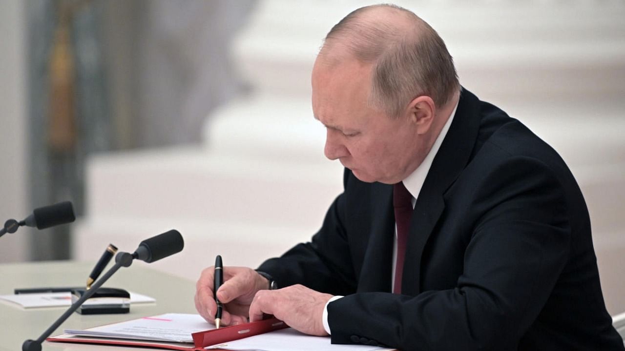 Russian President Vladimir Putin signs a document recognising the independence of separatist regions in eastern Ukraine in the Kremlin. Credit: AP/PTI Photo