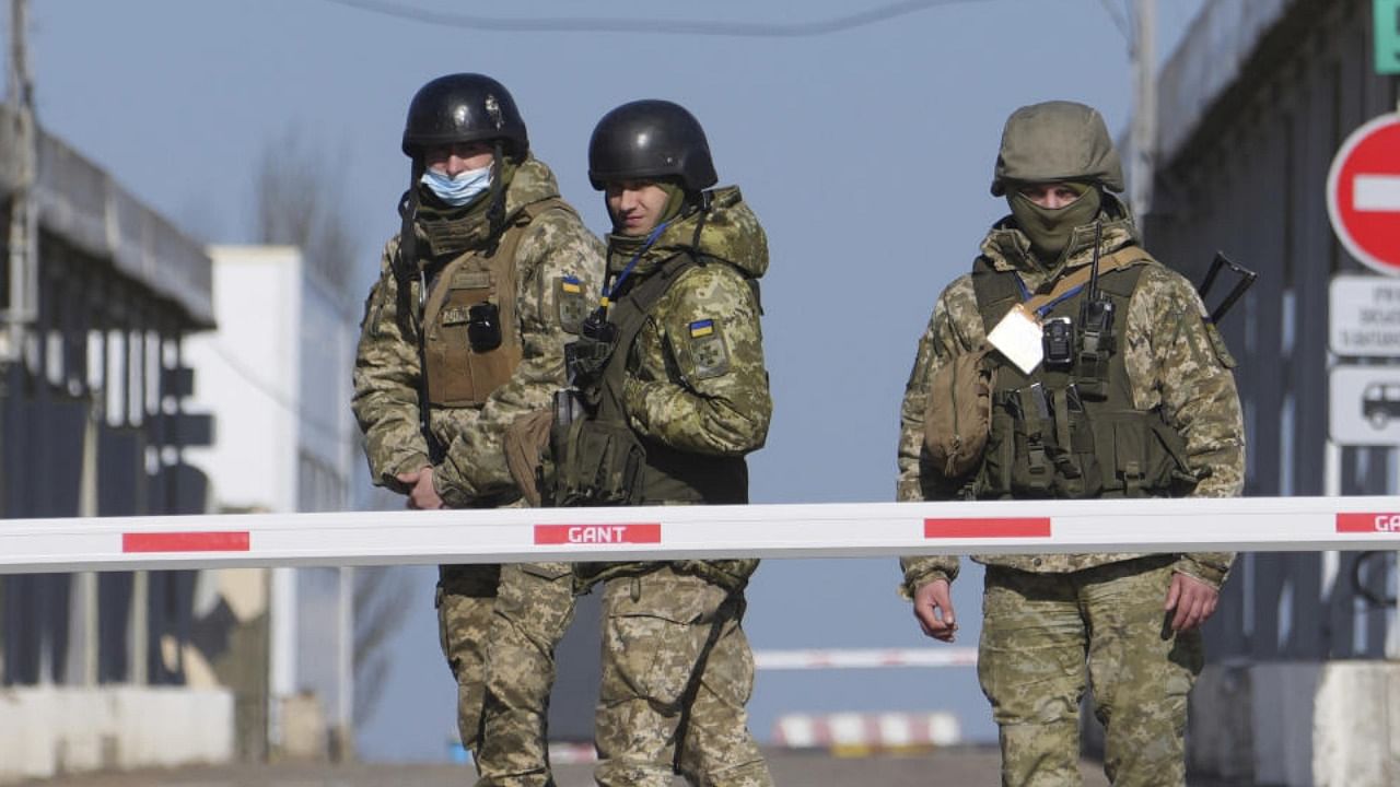 Ukrainian border guards stand at a checkpoint from territory controlled by Russia-backed separatists to the territory controlled by Ukrainian forces in Novotroitske, eastern Ukraine, Monday, Feb. 21, 2022. Credit: AP/PTI Photo