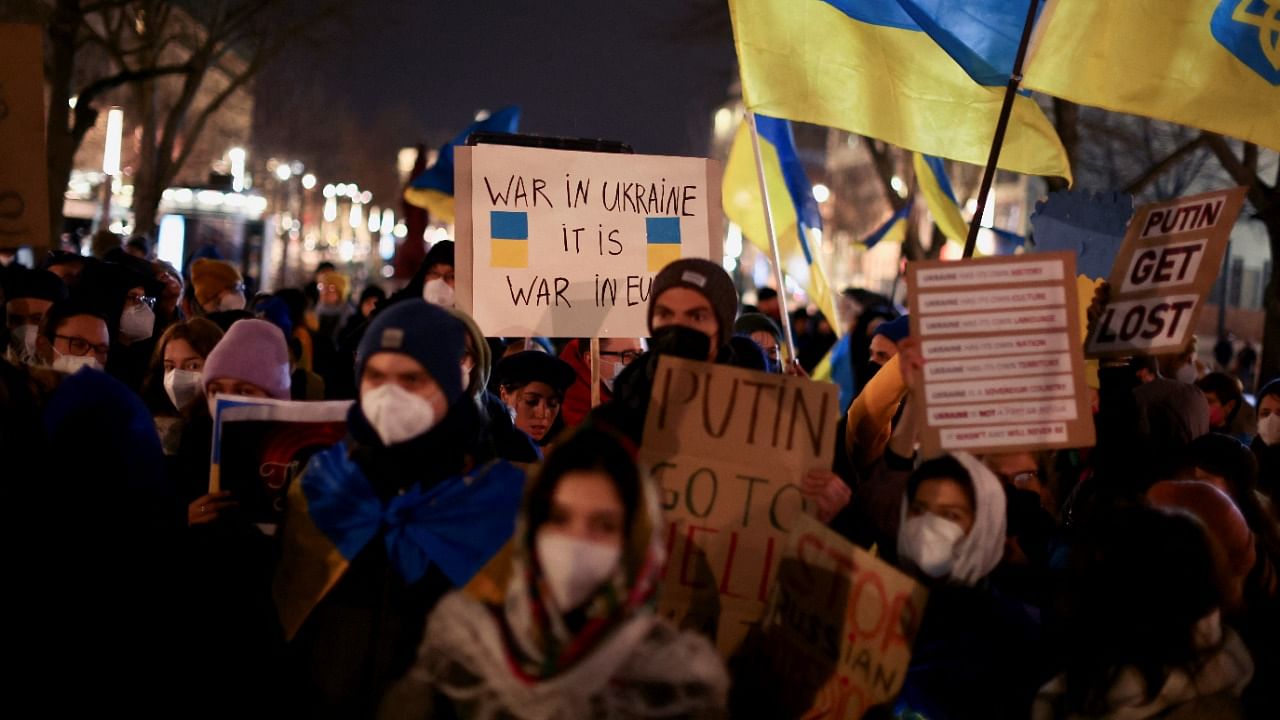 Demonstrators hold placards and wave Ukrainian flags during an anti-war protest in front of the Russian embassy in Berlin, Germany, February 22, 2022. Credit: Reuters Photo