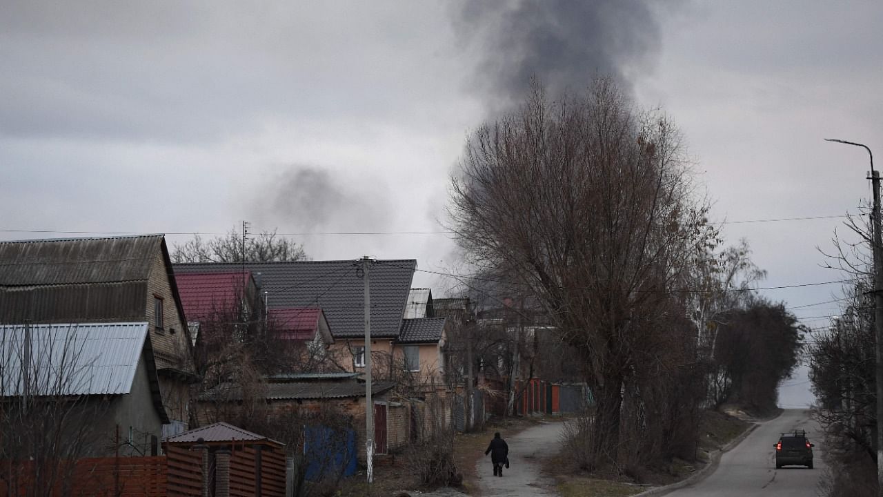 A local resident walks in a street as smoke rises near the town of Hostomel and the Antonov Airport, in northwest Kyiv. Credit: AFP File Photo