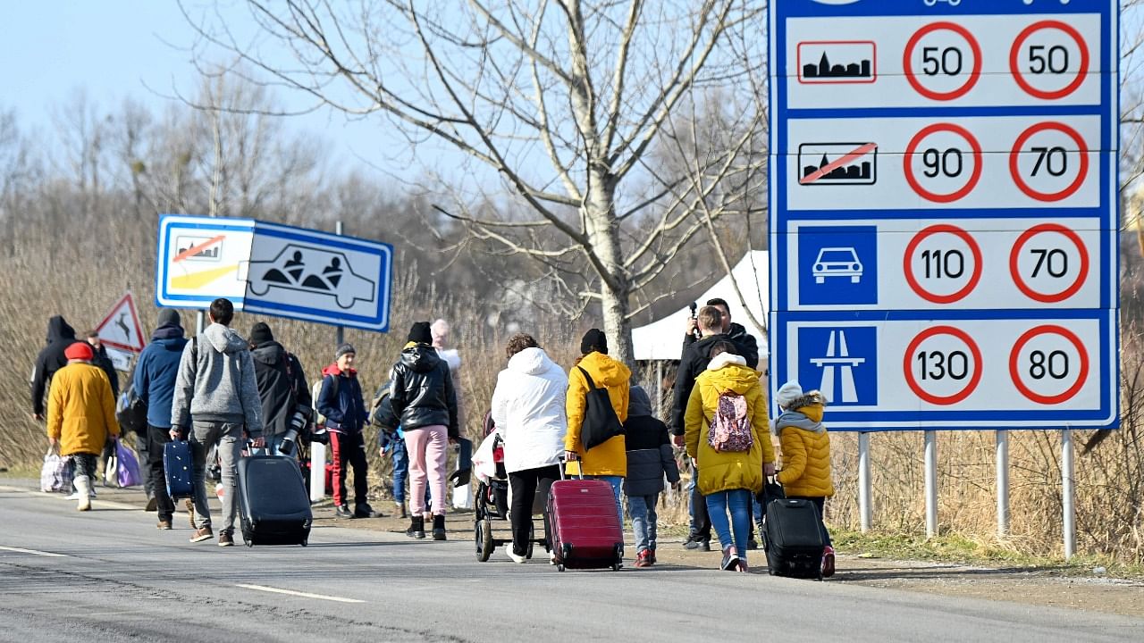 Ukrainian families fleeing the conflict in their country are seen walking with their luggage after crossing the Hungarian-Ukrainian border. Credit: AFP Photo