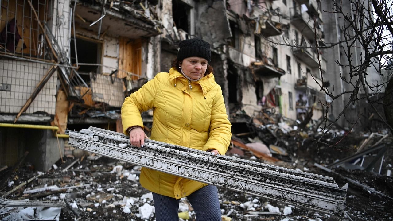 A woman clears debris at a damaged residential building at Koshytsa Street, a suburb of the Ukrainian capital Kyiv. Credit: AFP Photo
