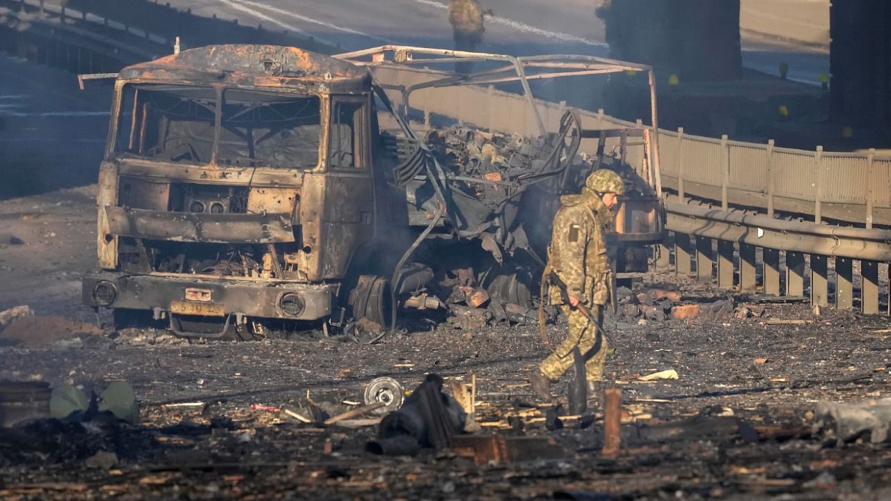 A Ukrainian soldier walks past debris of a burning military truck, on a street in Kyiv. Credit: AP/PTI File Photo