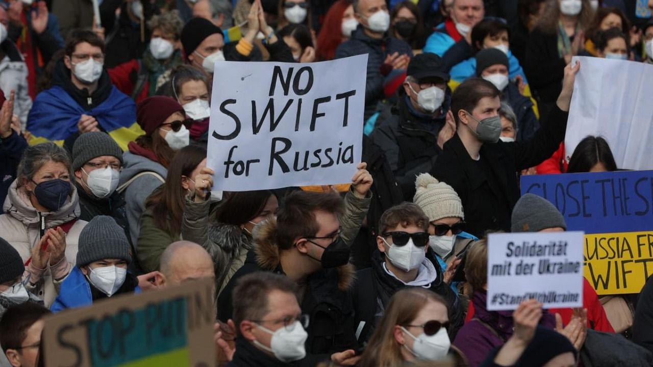 A protester holds a placard reading "No SWIFT for Russia" during a rally against Russia's invasion of Ukraine on February 26, 2022, in Frankfurt am Main, western Germany. Credit: AFP Photo