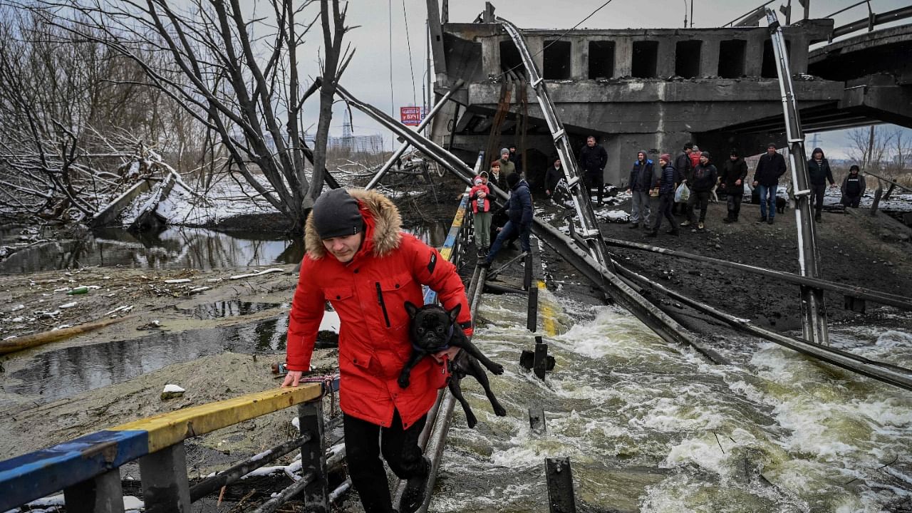 Civilians cross a river on a blown up bridge on Kyiv’s northern front. Credit: AFP Photo