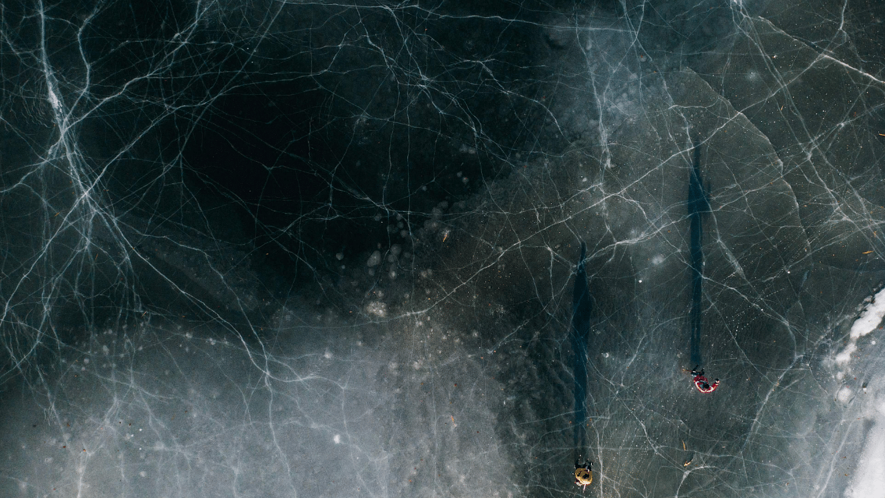 An aerial view shows two men skating on a frozen lake. Credit: AFP Photo