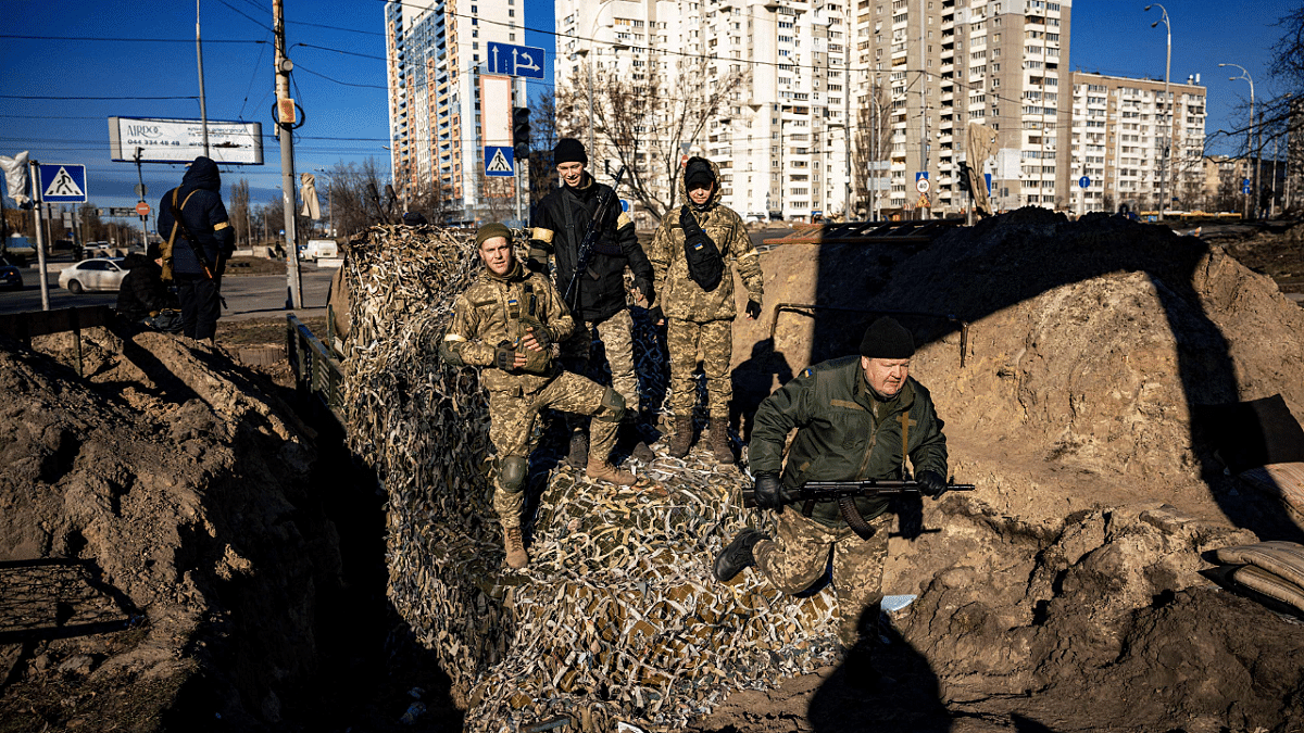 Kyiv residents and volunteers stand on top of APC while they prepare a rear post with trenches in Kyiv. Credit: AFP Photo