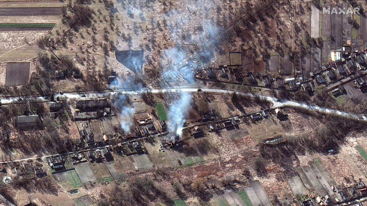 This Maxar satellite image taken and released on February 28, 2022 shows part of a military convoy and burning homes, northwest of Ivankiv, Ukraine. Credit: AFP Photo