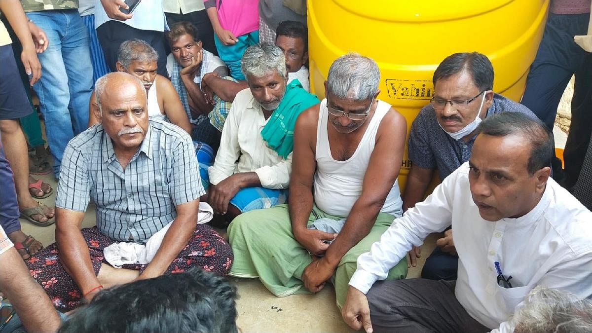 Villagers console Shekarappa Gyanagoudar (in white vest) at his house at Chalageri in Haveri district after the news of the death of his son Naveen in shelling in Ukraine broke out on Tuesday. Credit: DH Photo