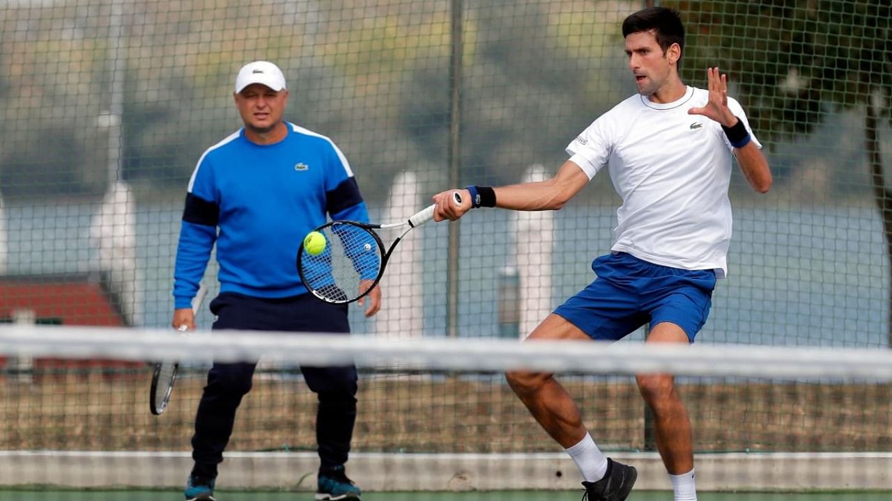 Serbia's Novak Djokovic returns the ball while his coach Marin Vajda looks on during a training session. Credit: AFP Photo