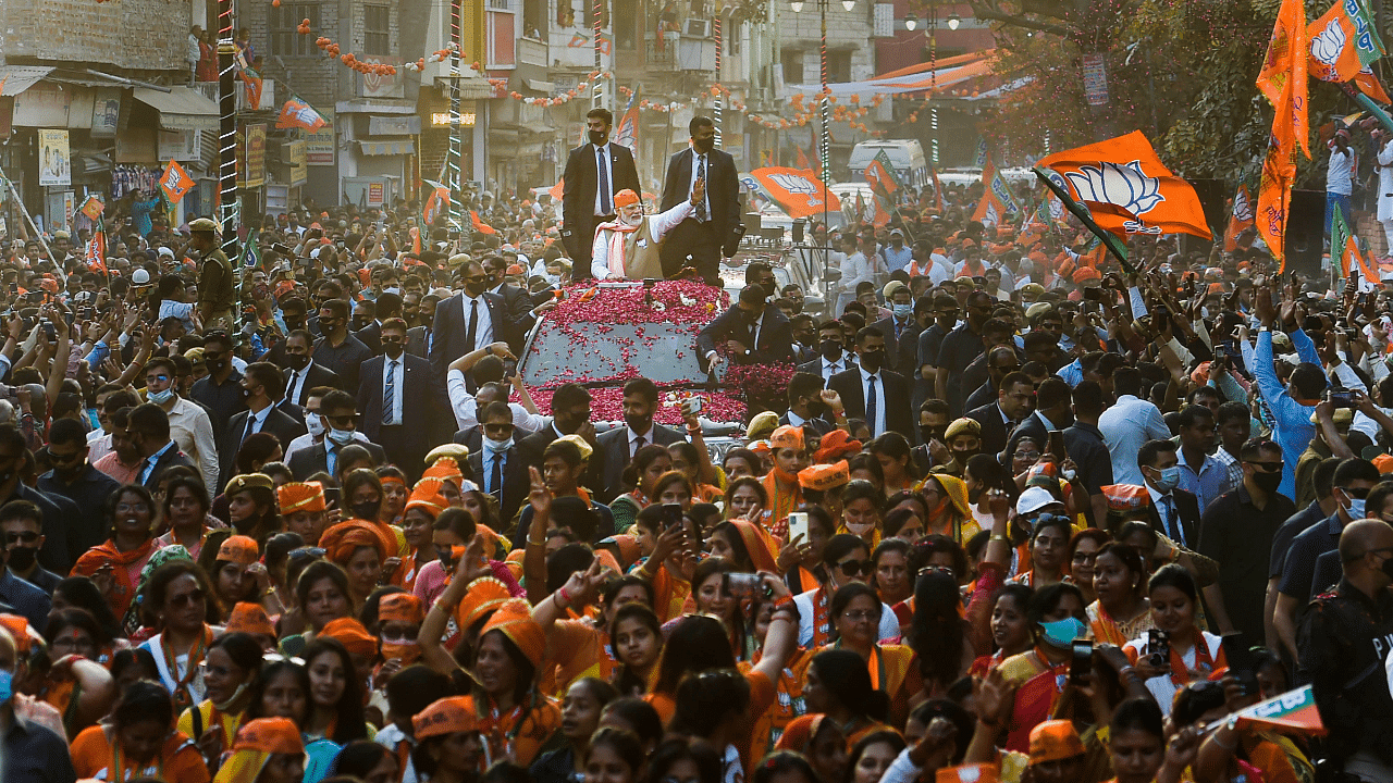 Prime Minister Narendra Modi waves at the supporters during a roadshow for the seventh and last phase of UP Assembly elections. Credit: PTI Photo