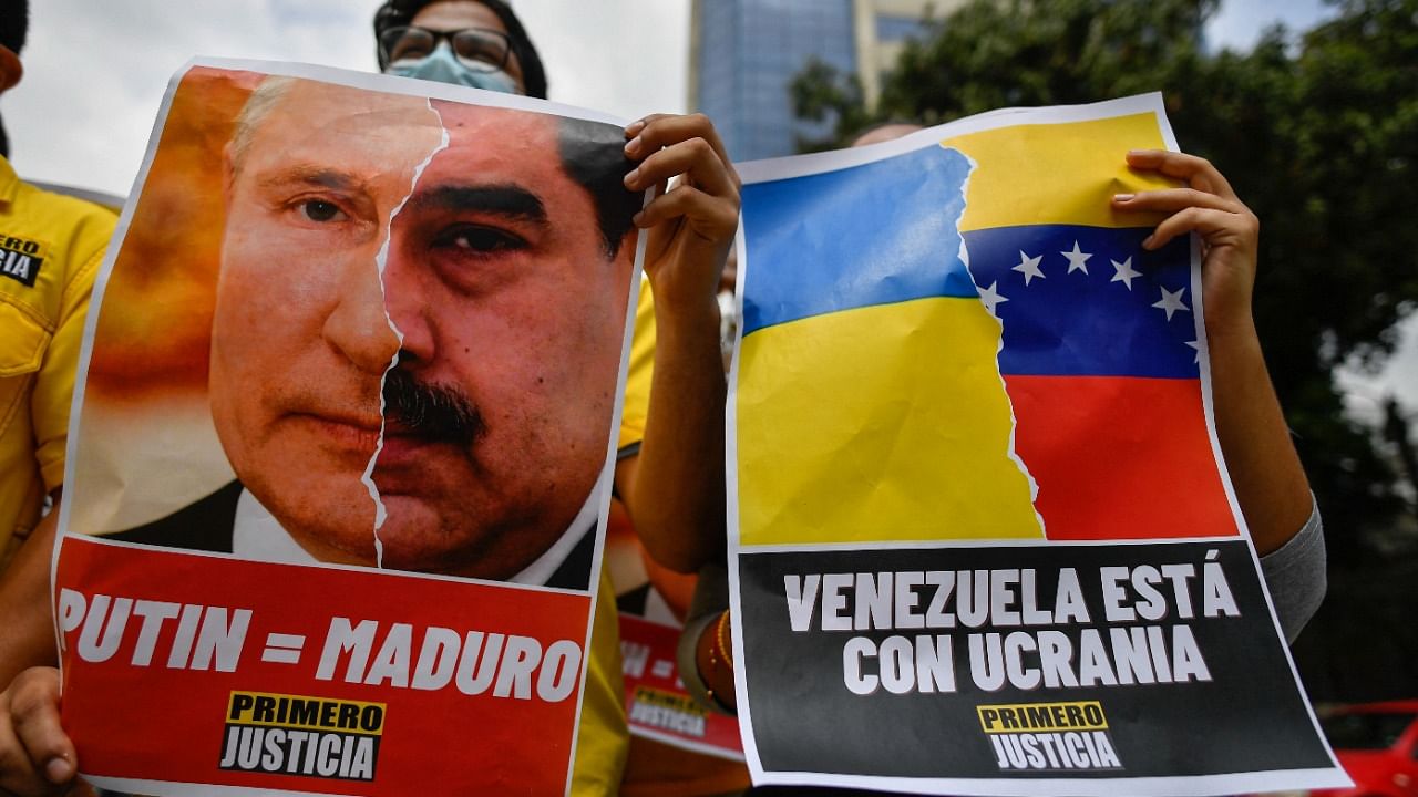 An activist member of opposition party Primero Justicia holds a placard showing the face of Russian President Vladimir Putin and Venezuelan President Nicolas Maduro during a protest against the Russian invasion in Ukraine, in Caracas on March 4, 2022. Credit: AFP Photo