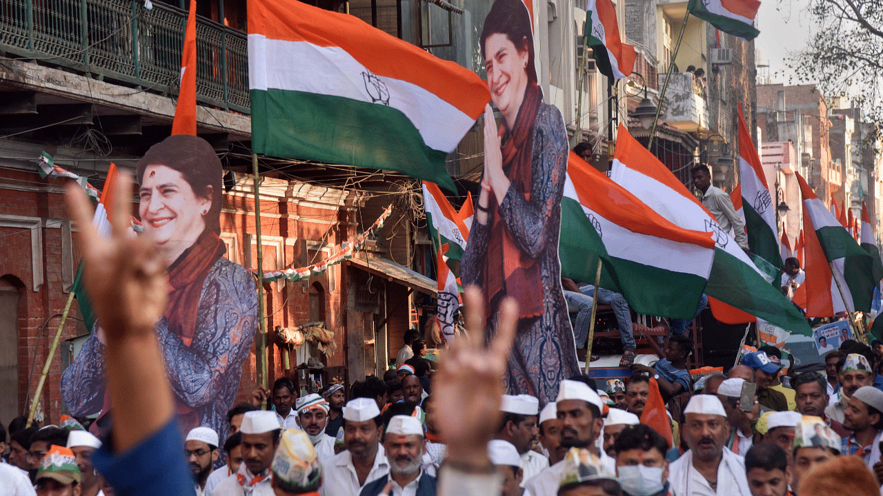 Congress workers holding the party flag and a cut-out of AICC General Secretary Priyanka Gandhi Vadra, take out an election campaign rally for the seventh and last phase of UP Assembly elections. Credit: PTI Photo