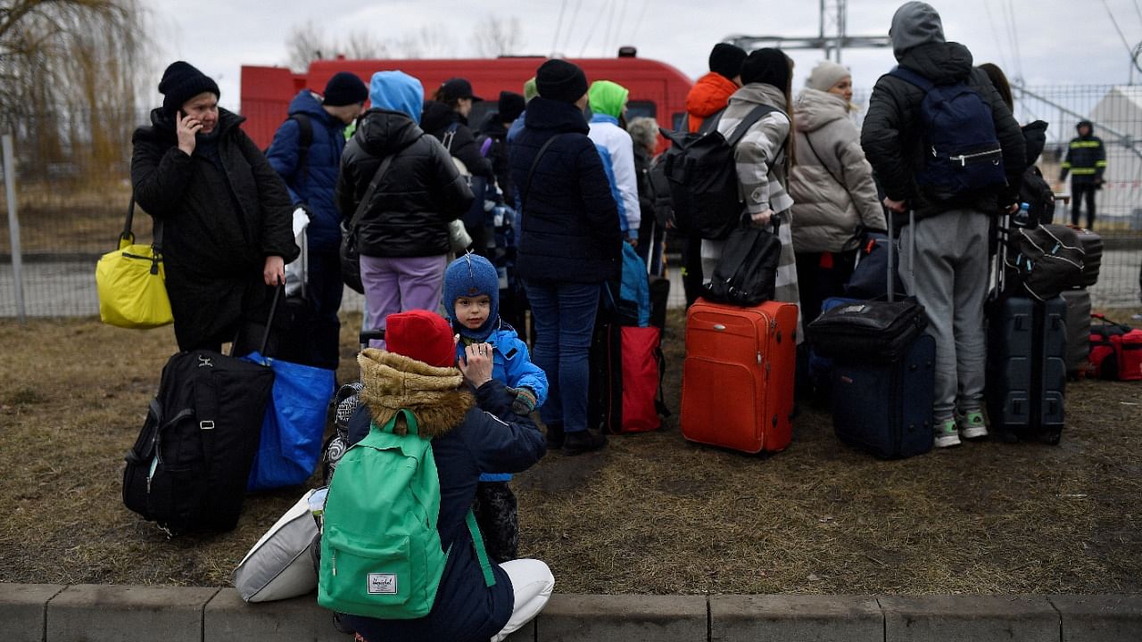 Families wait for transport after fleeing from Ukraine to Romania, following Russia's invasion of Ukraine, at the border crossing in Siret. Credit: Reuters photo