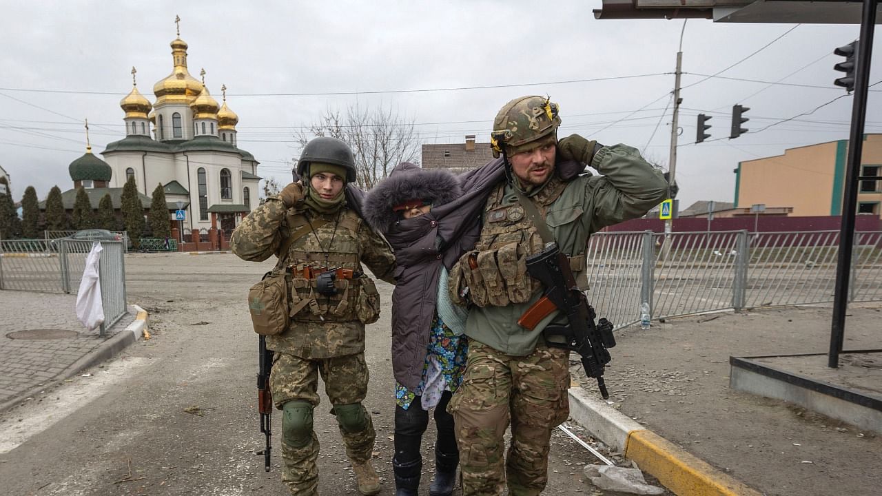 Ukrainian servicemen help an elderly woman, in the town of Irpin, Ukraine. Credit: AP Photo