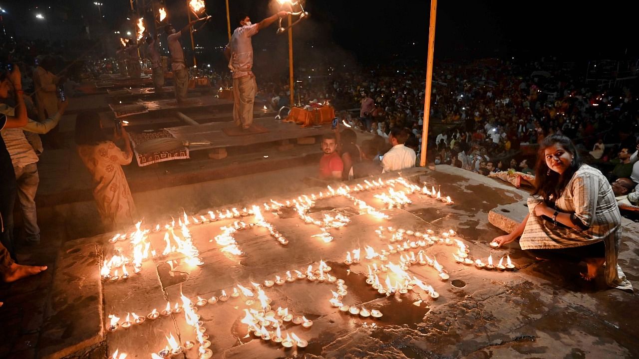 Devotees light earthern lamps as they perform 'aarti' on the banks of Ganga river, at Dashashwamedh Ghat in Varanasi, Monday, March 6, 2022. Credit: PTI Photo