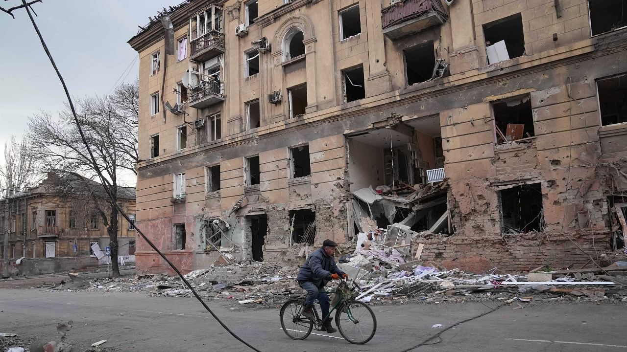  A man rides a bicycle in front of an apartment building that was damaged by shelling in Mariupol, Ukraine. Credit: AP/PTI Photo
