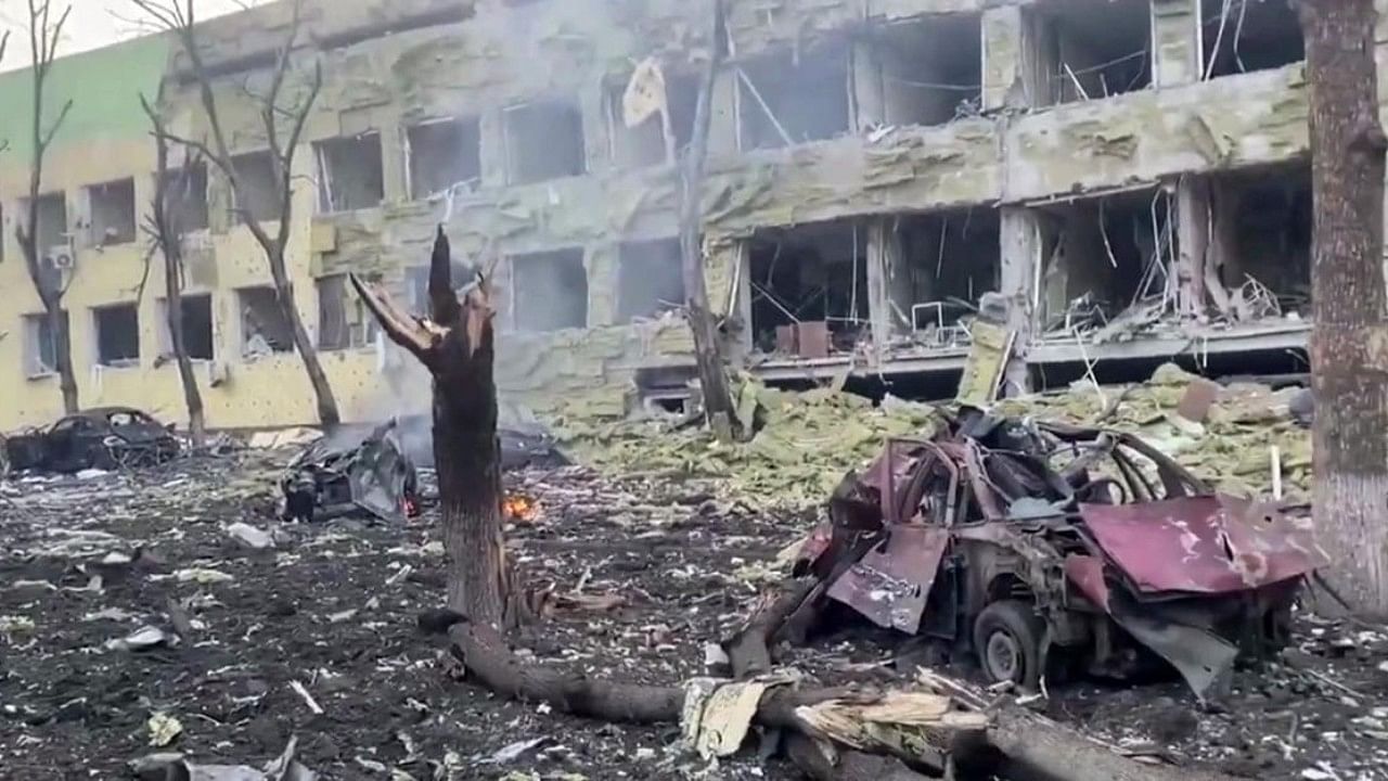 This video grab from a handout footage taken and released by the the National Police of Ukraine on March 9, 2022, shows a damaged building of a children's hospital, destroyed cars and debris on ground following a Russian air strike in the southeastern city of Mariupol. Credit: AFP File Photo