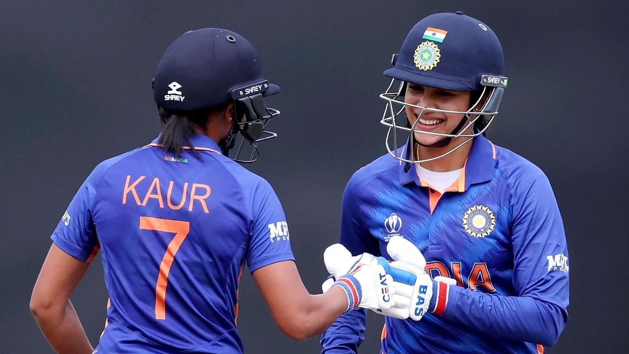 Smriti Mandhana (R) celebrates hitting a boundary with batter Harmanjot Kaur during India's Women's World Cup clash against West Indies. Credit: AFP Photo