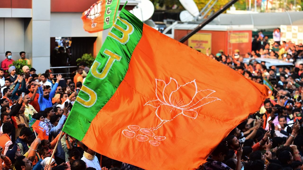 BJP supporters wave their flag as they celebrate party's win in Uttar Pradesh Assembly elections outside the party office in Lucknow. Credit: AFP File Photo