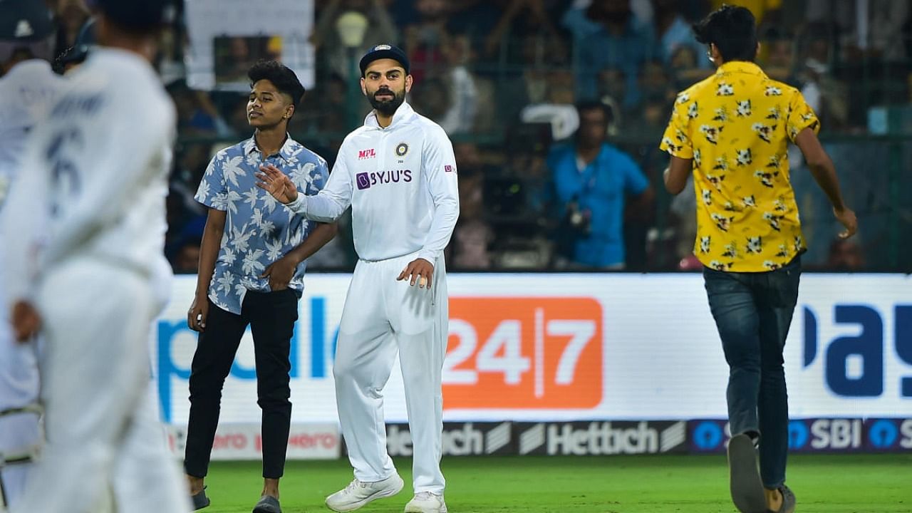 A pitch invader stands near Virat Kohli as another rushes towards him, during the second day of the second test cricket match between India and Sri Lanka, at Chinnaswamy Stadium in Bengaluru. Credit: PTI Photo