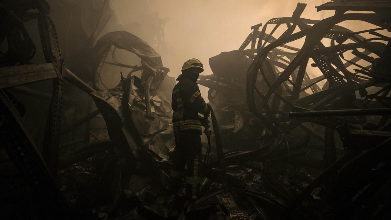 A Ukrainian firefighter drags a hose inside a large food products storage facility which was destroyed by an airstrike in the early morning hours on the outskirts of Kyiv, Ukraine, Sunday, March 13, 2022. Credit: AP Photo