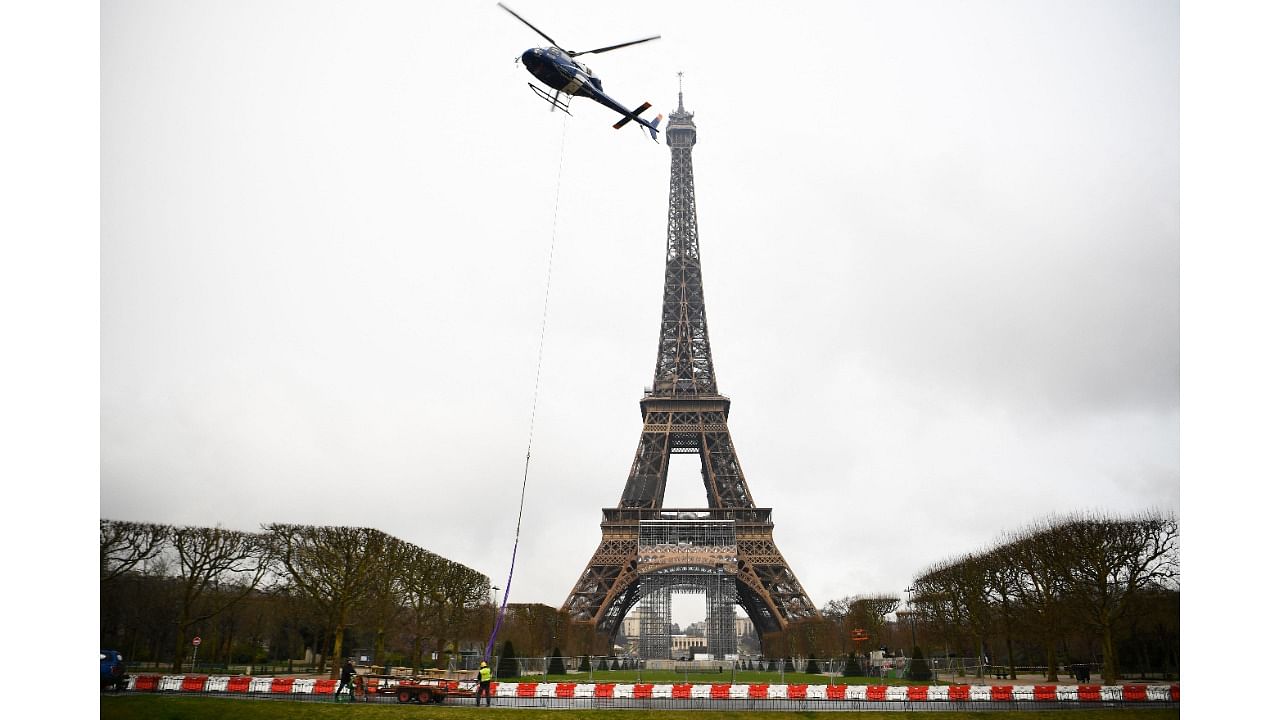 This photograph taken in Paris on March 15, 2022, shows a new antenna installed by a Eurocopter AS355N Ecureuil 2 at the top of the Eiffel Tower. Credit: Christophe ARCHAMBAULT/AFP