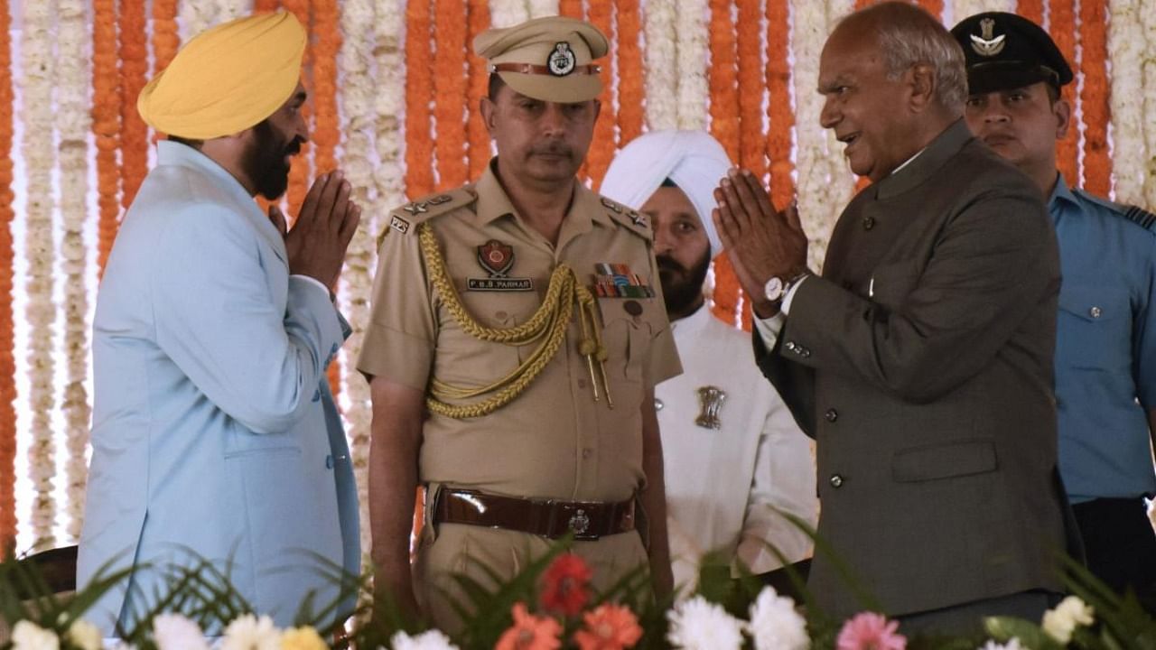 Bhagwant Mann (L) of Aam Aadmi Party (AAP) gestures to Punjab governor Banwarilal Purohit (2R) after taking the oath as 17th Chief Minister of Punjab during the swearing-in ceremony in Khatkar Kalan village. Credit: PTI Photo